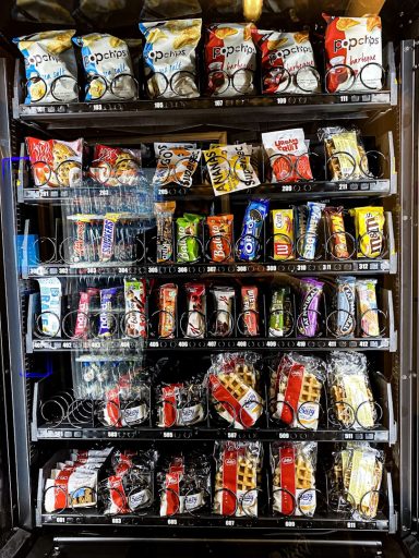 A vending machine filled with various snacks and drinks in colorful packaging.